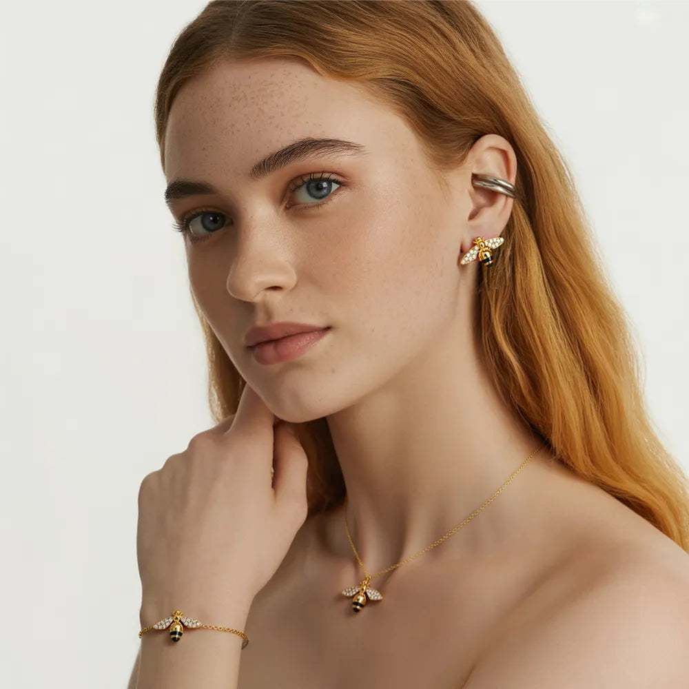 Model wearing the complete Apia Pavé Bee Charm Set, including necklace, bracelet, and stud earrings.