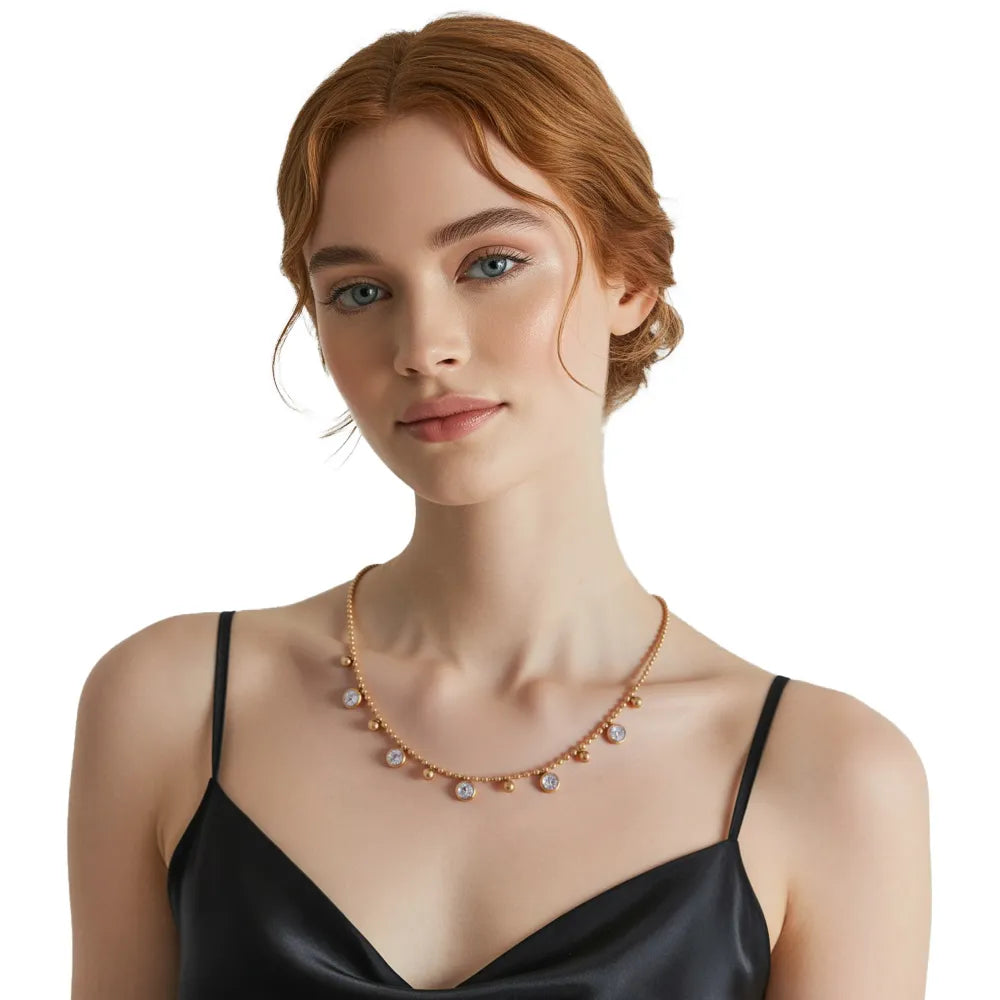 Model wearing a dainty gold drop necklace with white zirconia stones, showing the elegant collarbone length fit