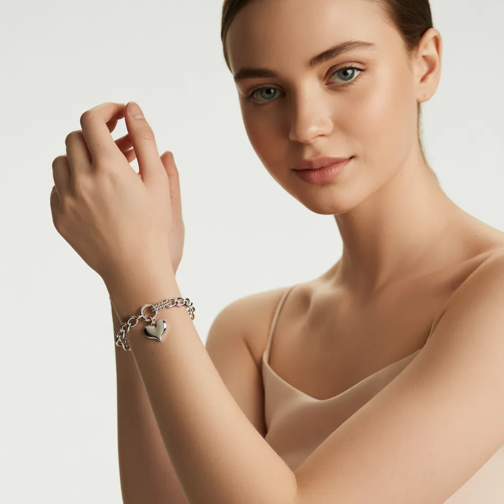 Woman with red hair showcasing the chic silver-tone bracelet with a heart charm.