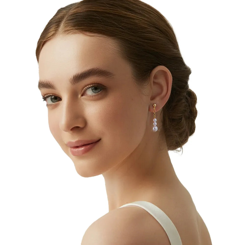 Close-up of model wearing the S925 silver graduated pearl linear earrings.