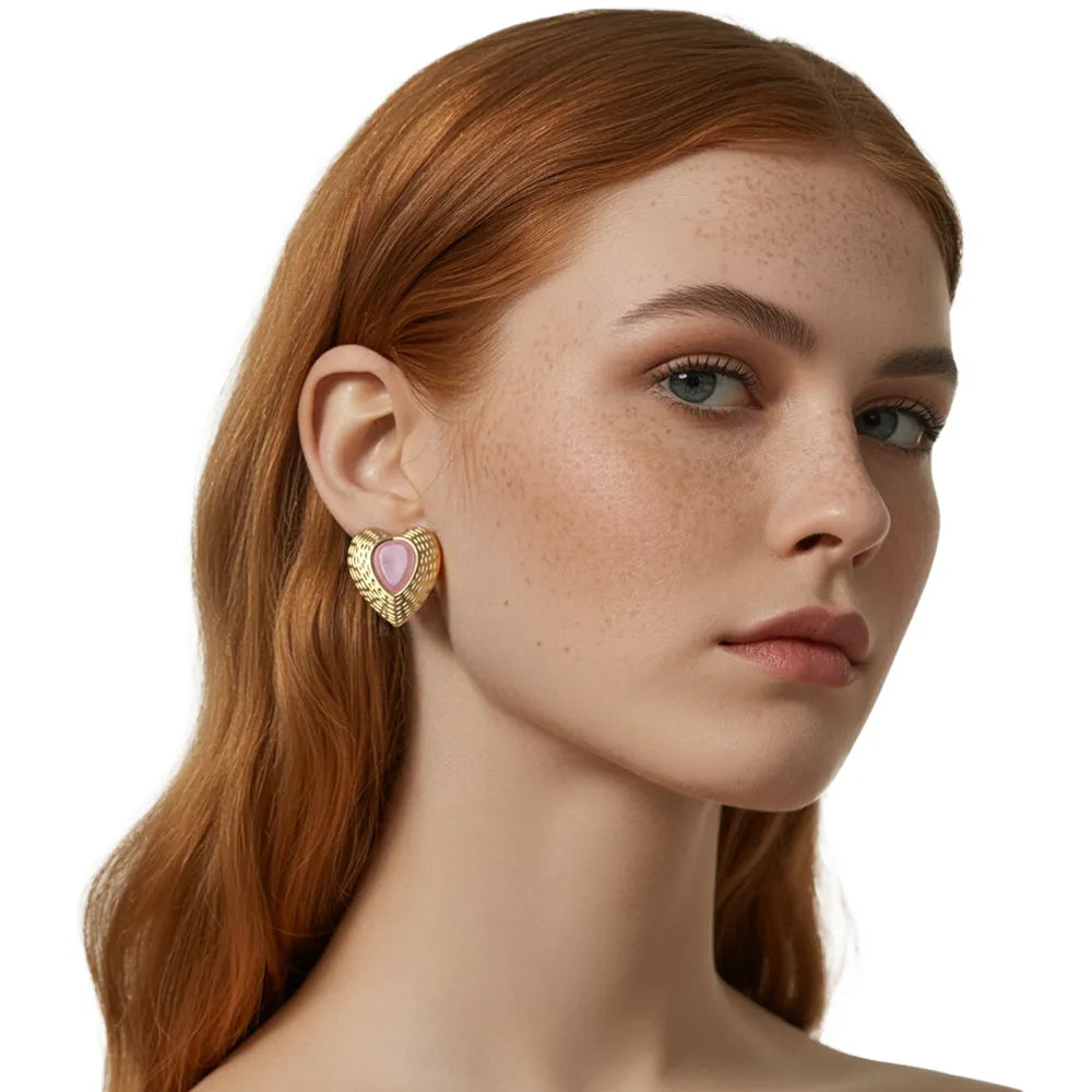 Side profile shot of a model wearing the pink cat eye gold heart earrings, highlighting the romantic color and textured metal finish