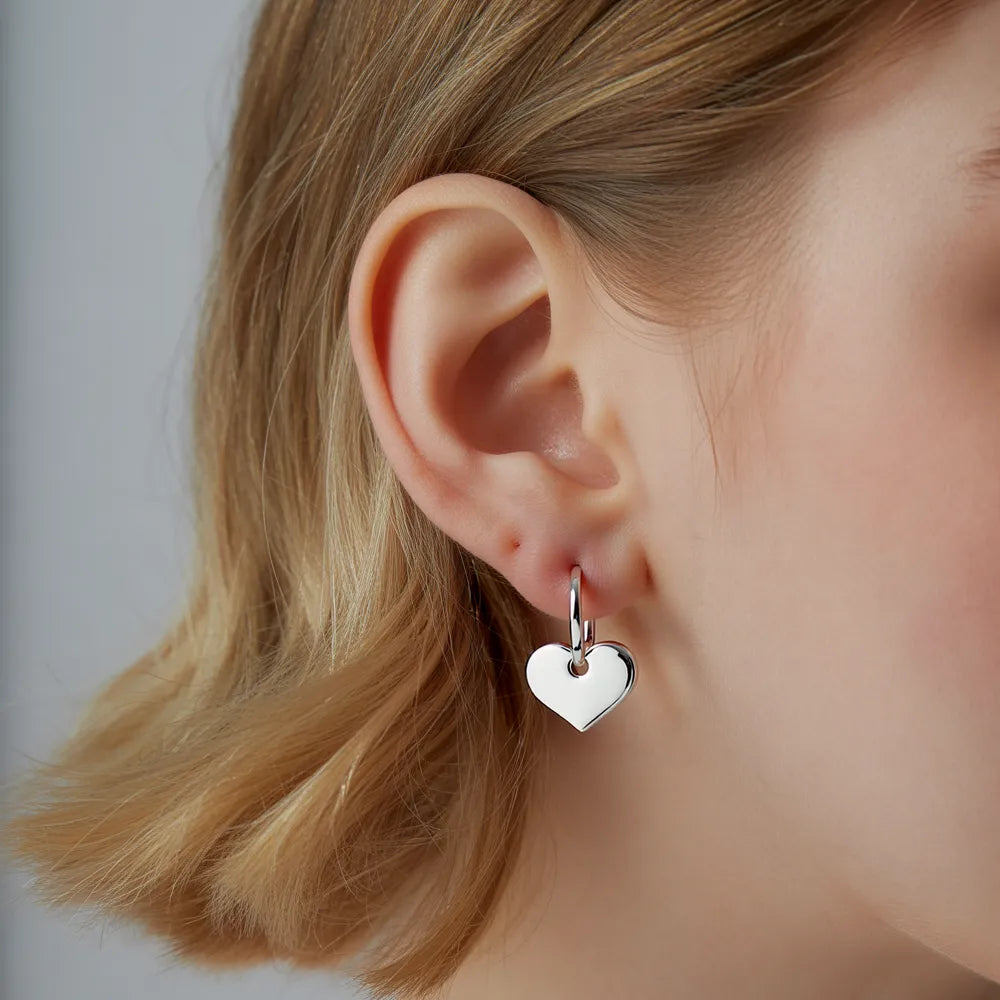 Hypoallergenic silver heart hoops worn by a model, perfect for everyday wear.