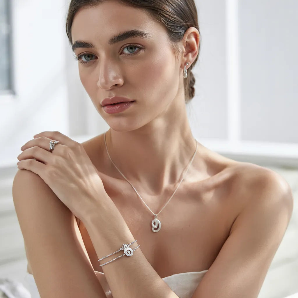 Elegant model wearing a luxury 925 sterling silver pendant necklace with layered silver bracelets and a statement ring.