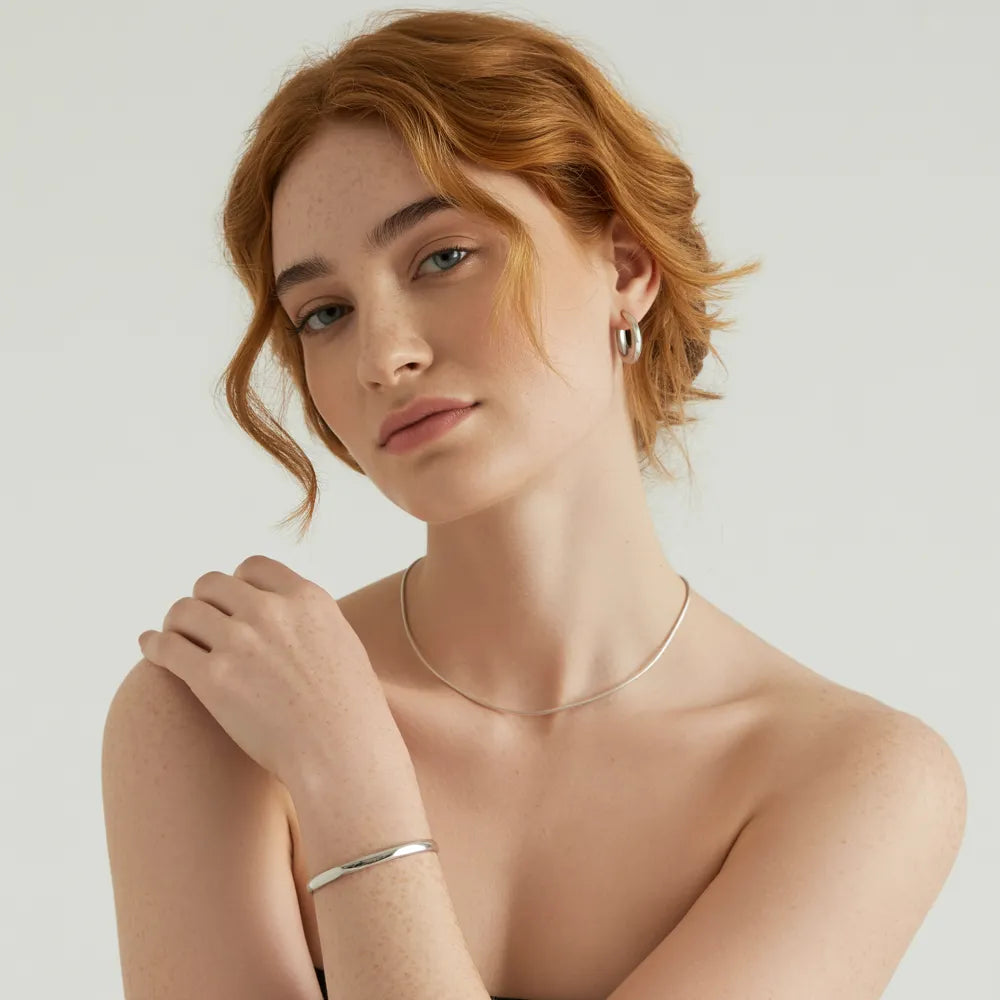 A model's wrist wearing a hypoallergenic stainless steel charm bracelet from the GlamBodyCandy collection for women.