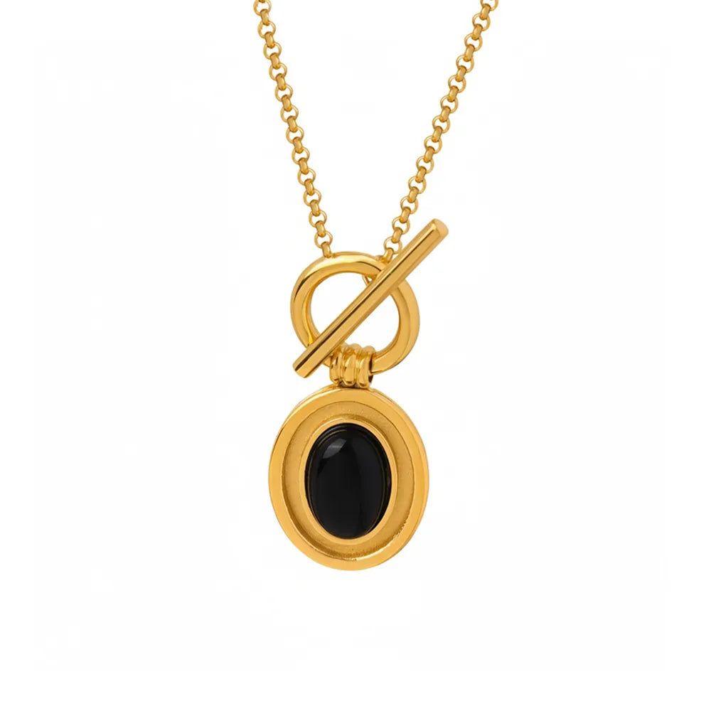 Studio shot of an 18K gold plated necklace featuring an oval natural black onyx pendant suspended from a front toggle clasp, isolated on white