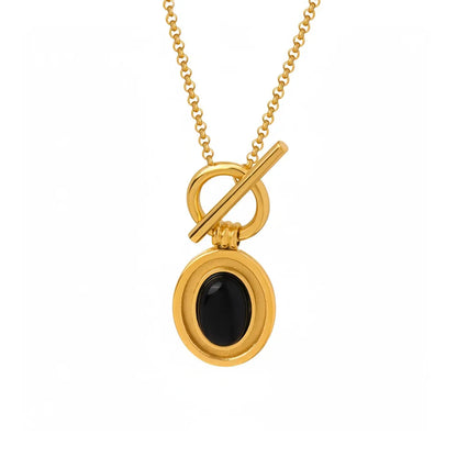 Studio shot of an 18K gold plated necklace featuring an oval natural black onyx pendant suspended from a front toggle clasp, isolated on white