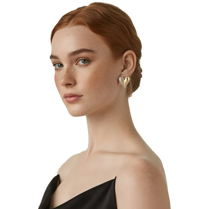 Close-up view of a model wearing the 18K gold pave heart stud earrings, highlighting the dual-texture shine on the earlobe.