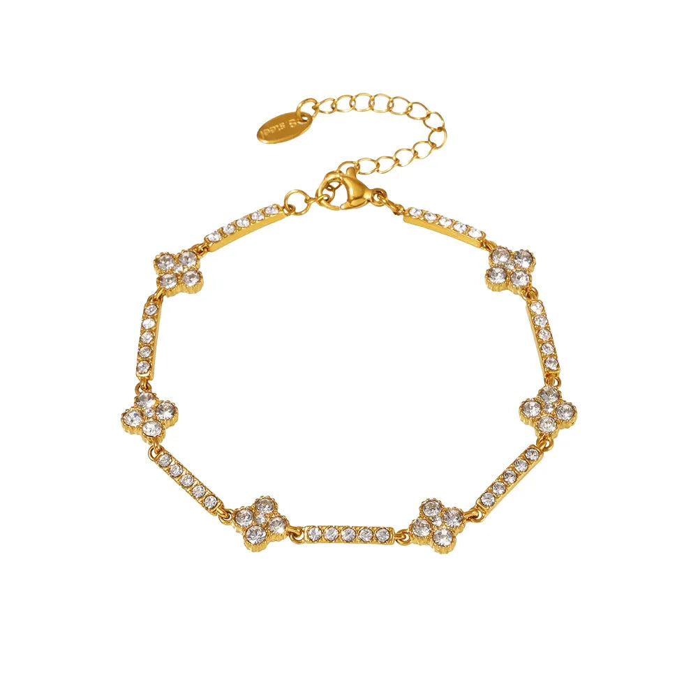 Studio shot of an 18K gold plated link bracelet featuring four-petaled flower charms alternating with crystal bars, isolated on white