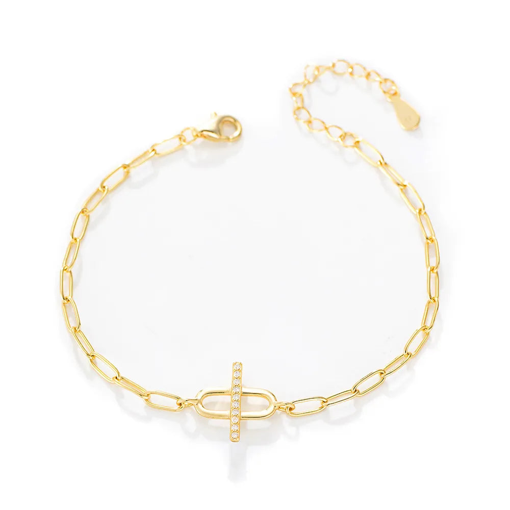 Gold plated paperclip chain bracelet featuring a crystal bar interlocking with an oval ring.
