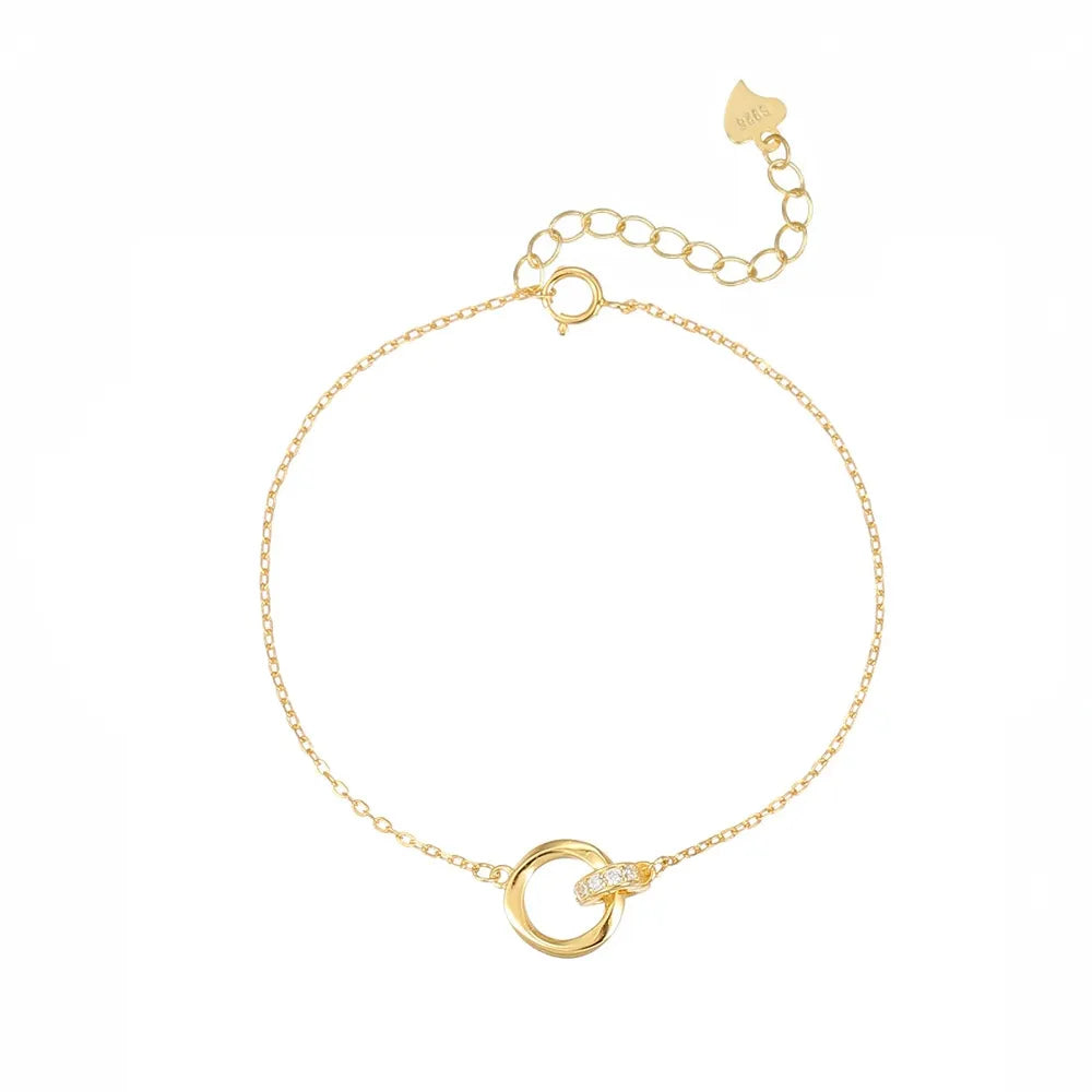 Studio shot of an 18K gold plated S925 sterling silver bracelet featuring interlocking Mobius rings with pave-set crystals, isolated on white