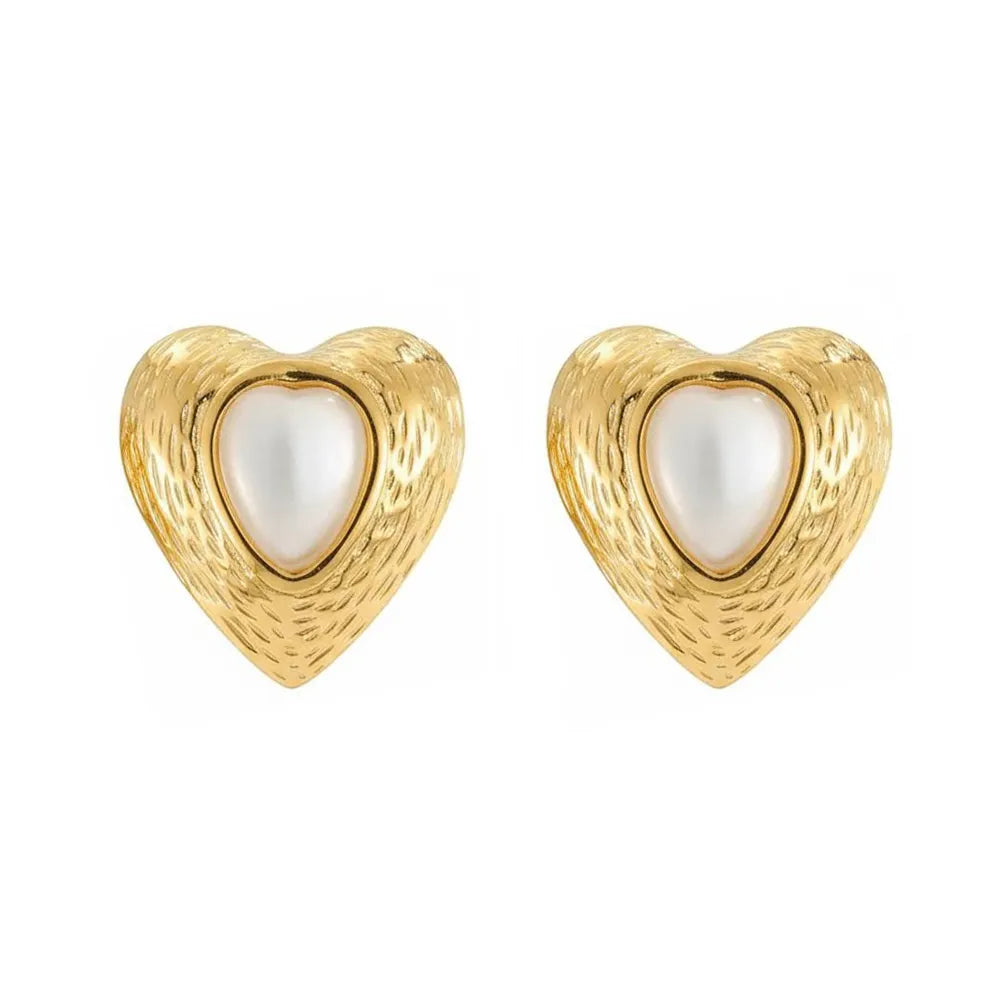 Close-up view of 18K gold plated heart-shaped stud earrings featuring a white cat eye stone center and textured gold frame, isolated on a white background.