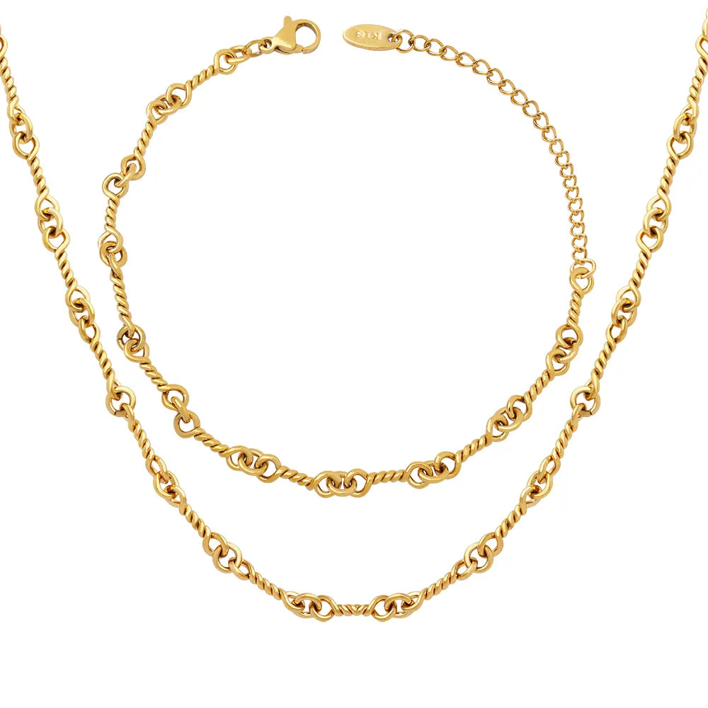 A flat lay of the complete Alia Interlocking Necklace and Bracelet Set in gold.