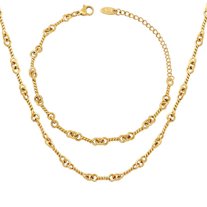 A flat lay of the complete Alia Interlocking Necklace and Bracelet Set in gold.