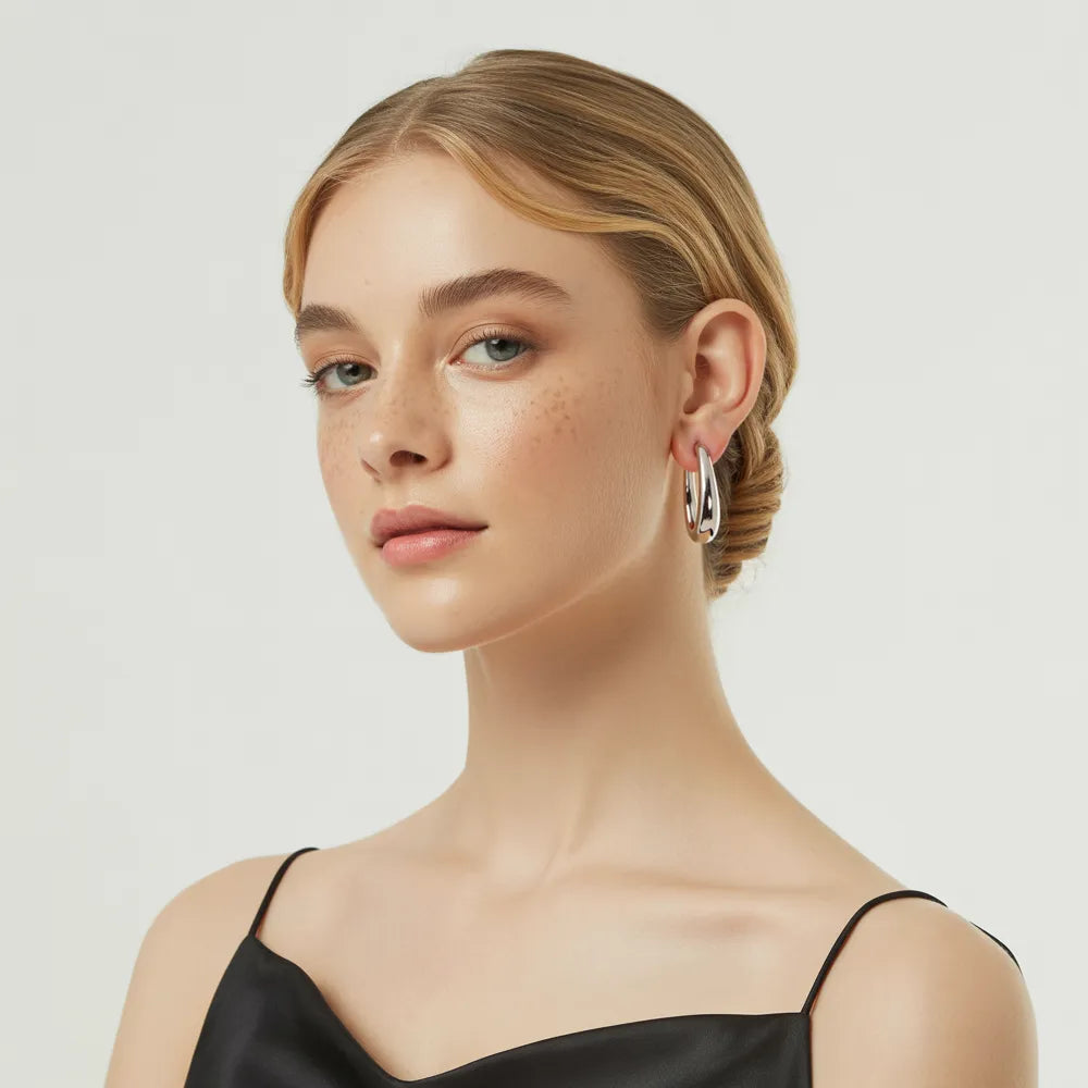 Model wearing the sleek, polished stainless steel Anya Sculptural Hoop Earrings.