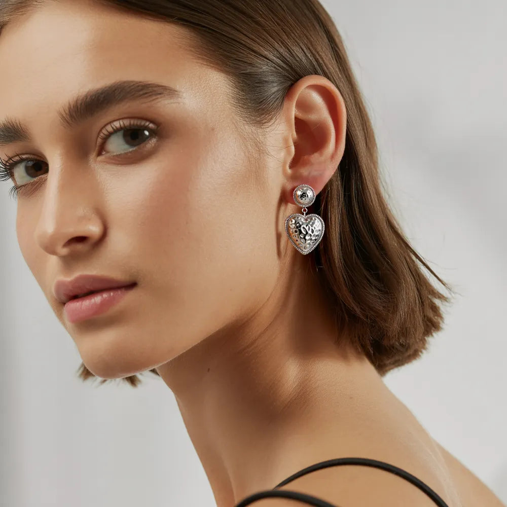 Model wearing the polished stainless steel Baroque Heart Drop Earrings.