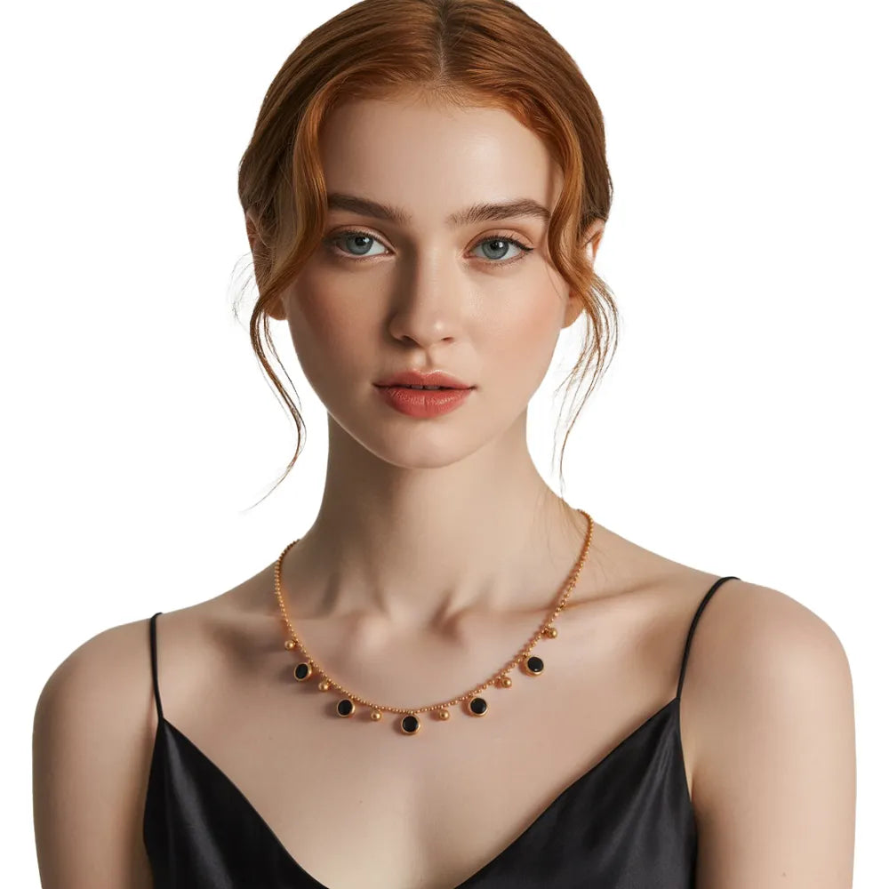 Woman wearing a black crystal fringe necklace in gold, styled with a black dress for a sophisticated look