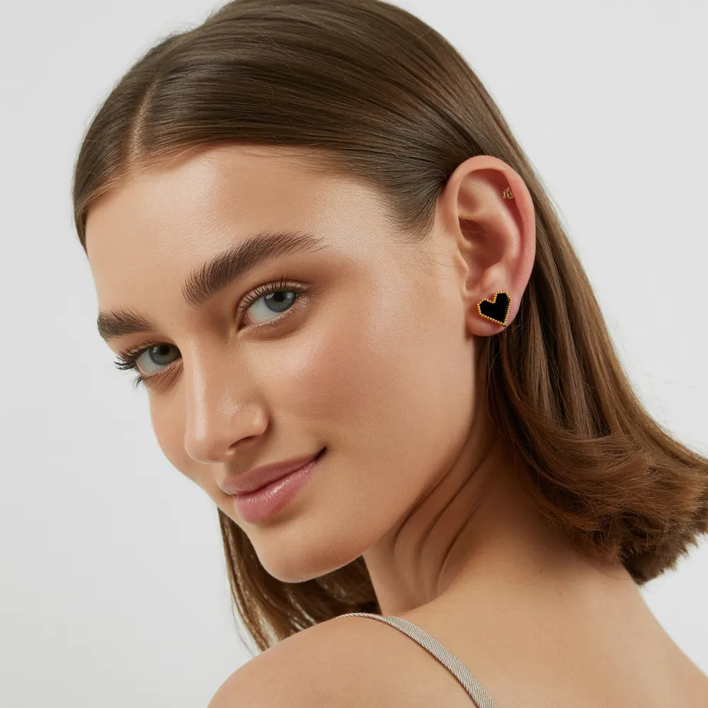 Model wearing romantic red heart gold stud earrings featuring a beaded vintage edge.