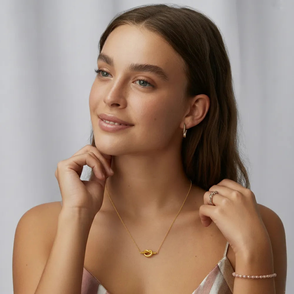 A close-up of the Elara Knot Heart Pendant resting on a model&