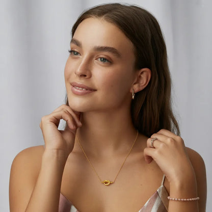 A close-up of the Elara Knot Heart Pendant resting on a model&