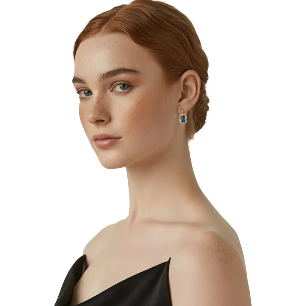 Model wearing elegant emerald-cut blue halo earrings with a black evening dress.