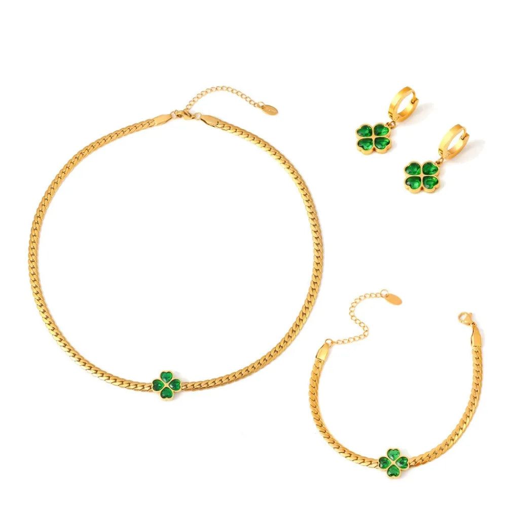 The complete Clover Emerald Green Jewelry Set in 18k gold, including the herringbone necklace, bracelet, and hoop earrings.