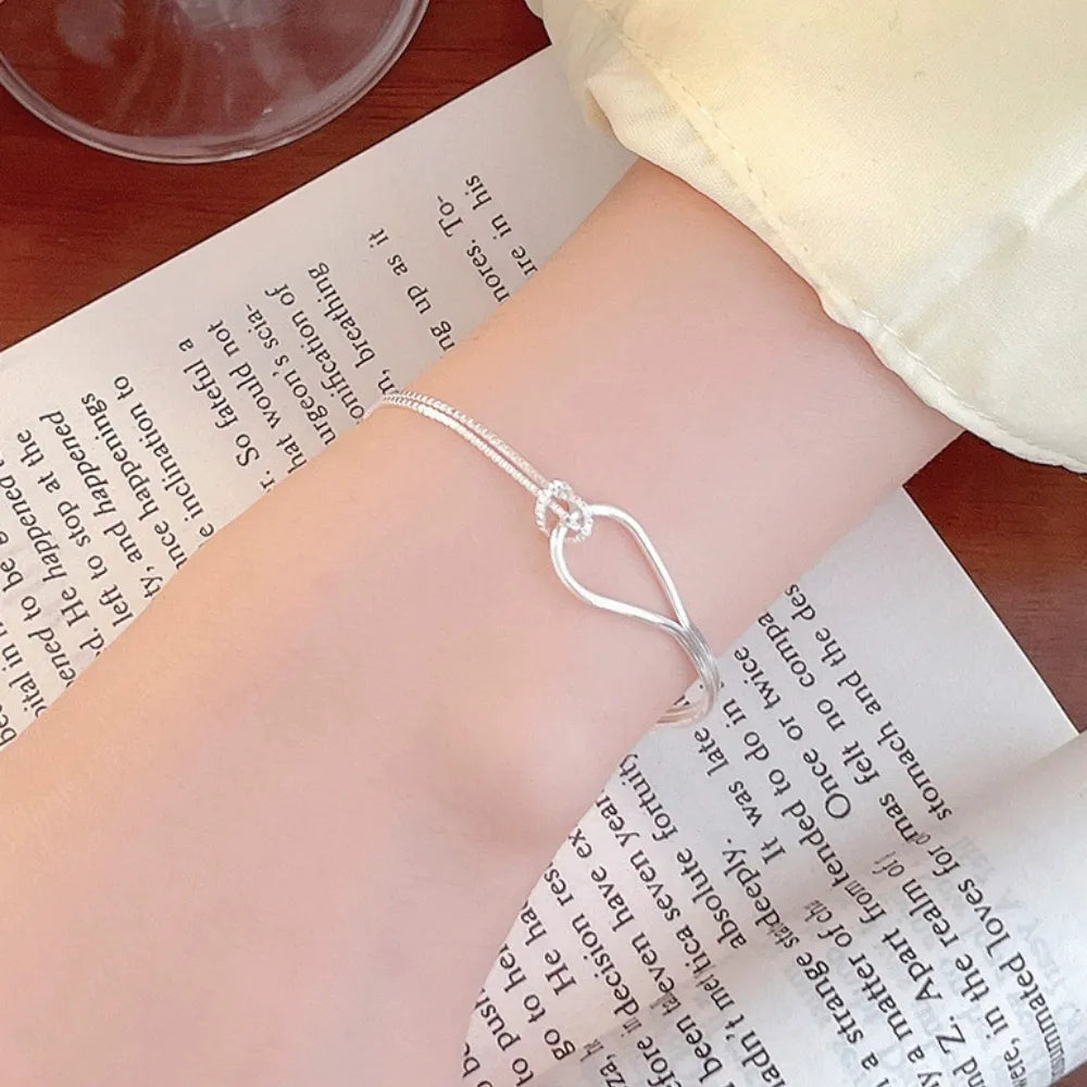Detailed view of the S925 silver bracelet showing the combination of a sleek rigid arc and a delicate box chain joined by a pave knot