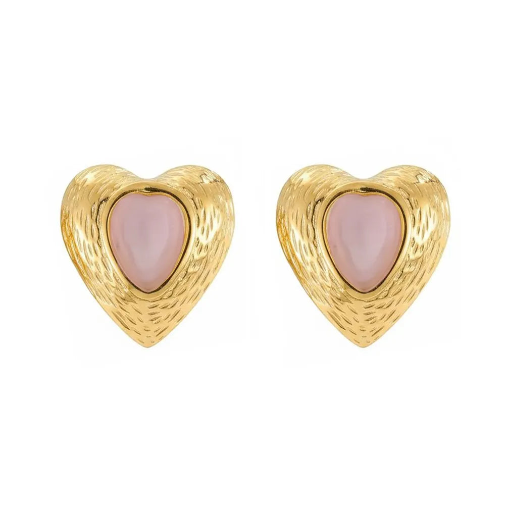 Pair of vintage-style 18K gold heart studs with a soft pink cat eye stone enclosed by a detailed gold border, against a white background.