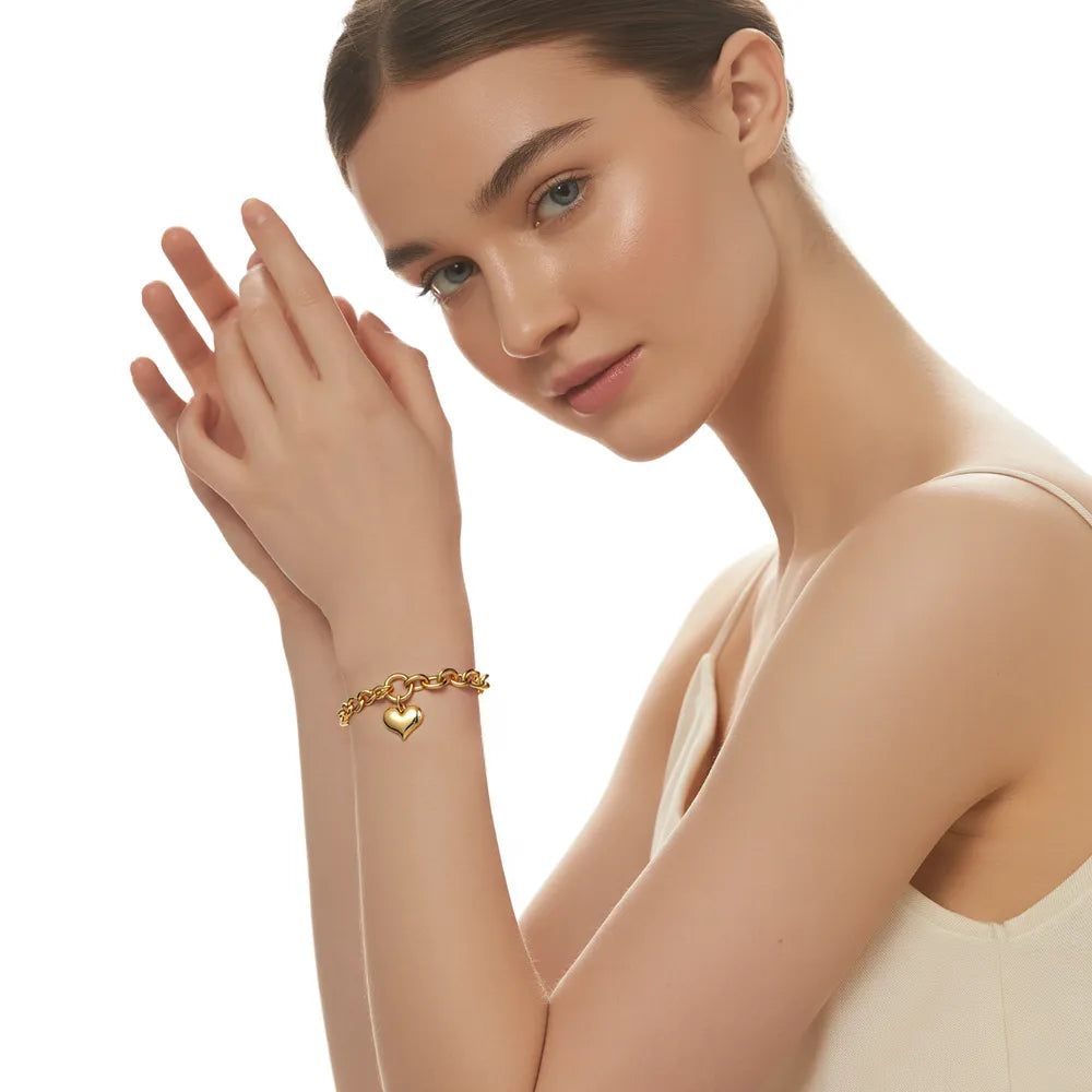 Model wearing the 18K gold Heart Charm Cuban Link Bracelet, showcasing its bold design.