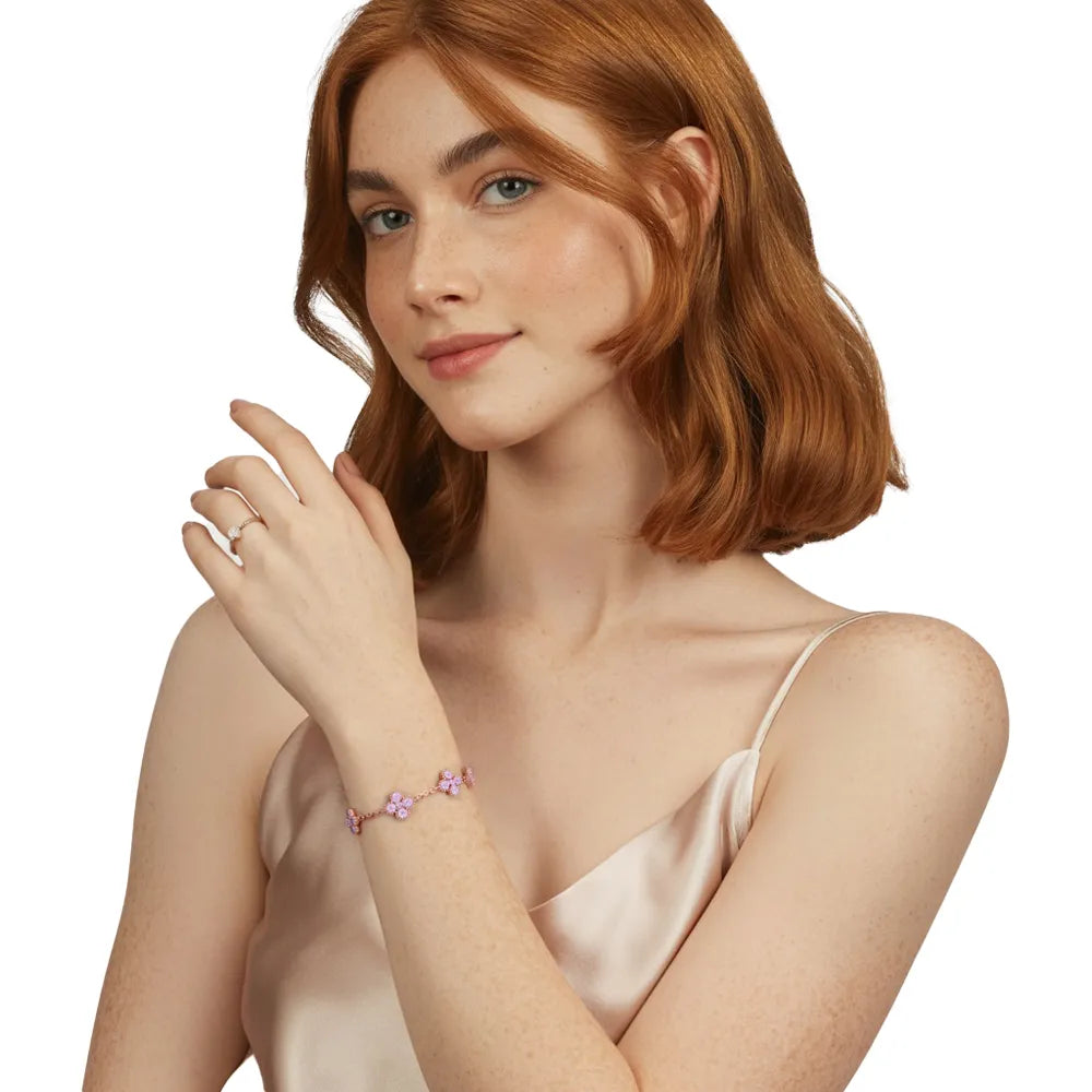 Model touching a delicate rose gold bracelet adorned with pink heart-shaped petals.