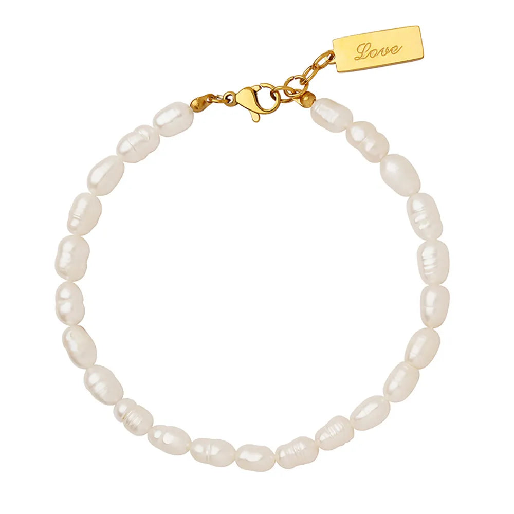 The Perla Station Bracelet in 18k gold plate, featuring lustrous pearls on a delicate chain, shown on a white background.