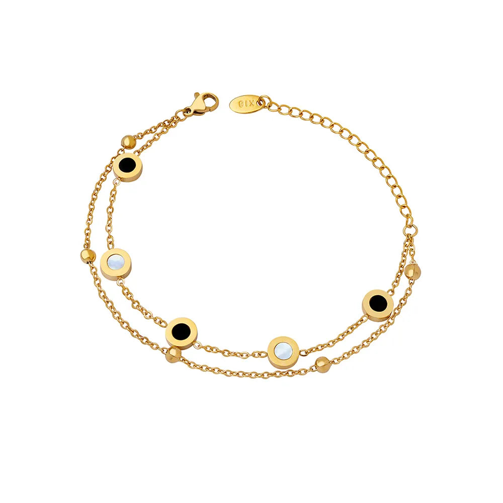 18K gold plated layered bracelet with mother of pearl and black onyx station charms on a white background