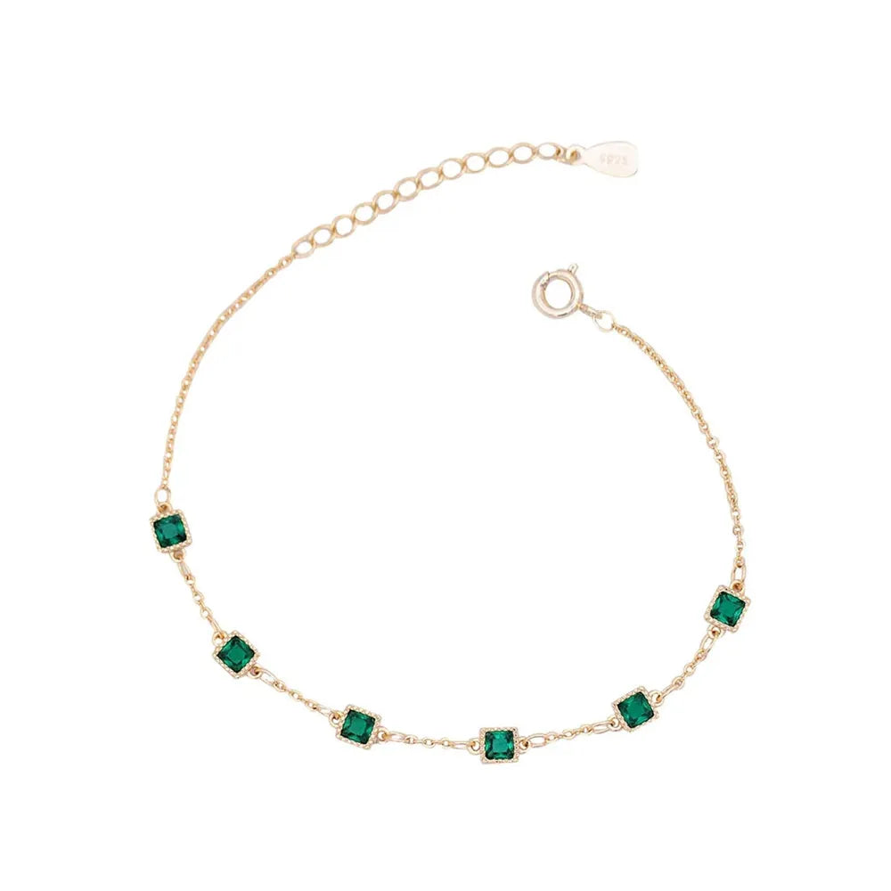 S925 sterling silver bracelet plated in 14K gold, featuring station-set emerald green square zircons on a white background.