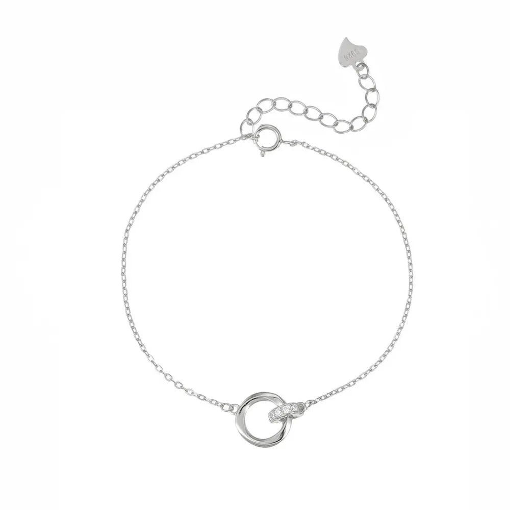 Studio shot of a minimalist S925 sterling silver bracelet with two intertwined circles—one polished and one encrusted with cubic zirconia