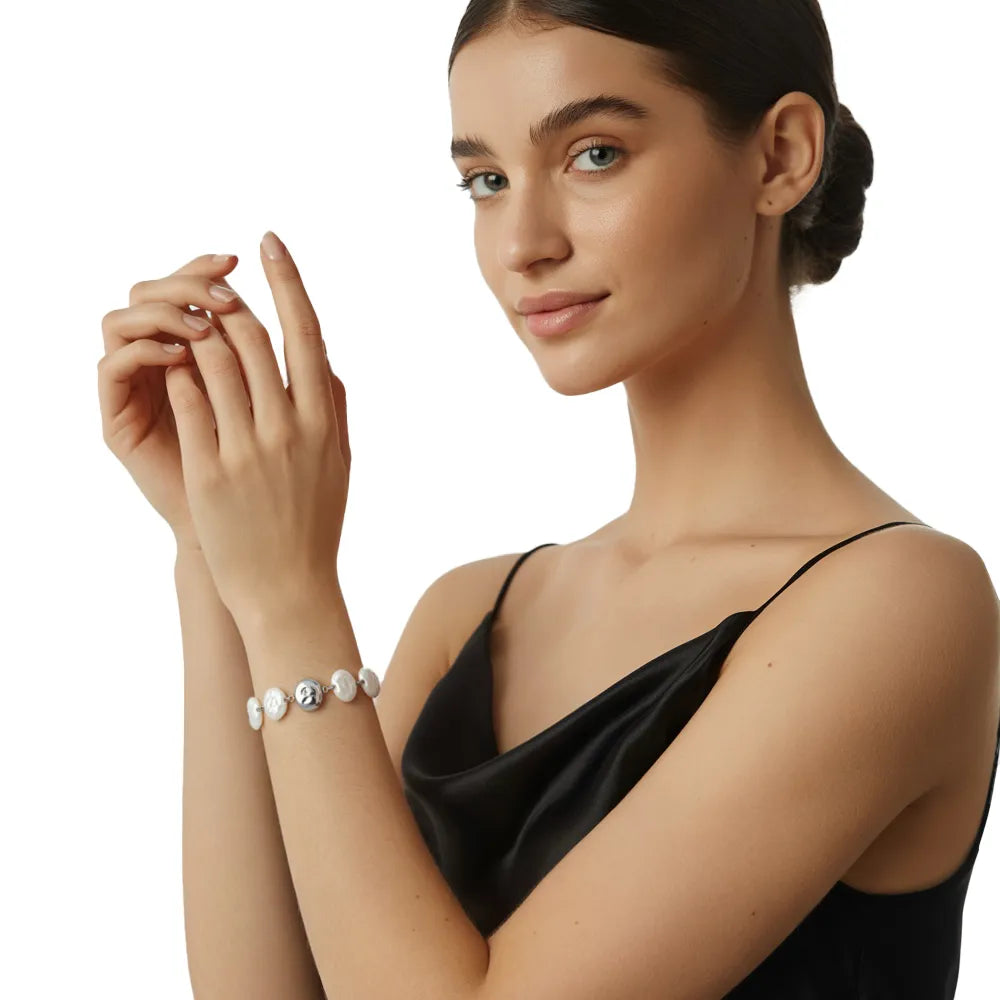 Close-up view of the silver stainless steel baroque pearl and abstract face bracelet worn on a woman&