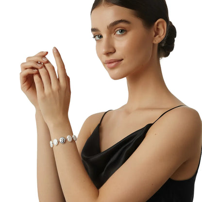 Close-up view of the silver stainless steel baroque pearl and abstract face bracelet worn on a woman&