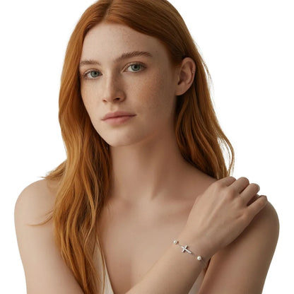Close-up of redhead model wearing the silver sideways cross and pearl bracelet.