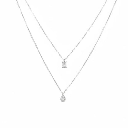 Silver double chain necklace with a geometric rectangle stone and a pear-cut zirconia drop, isolated on white