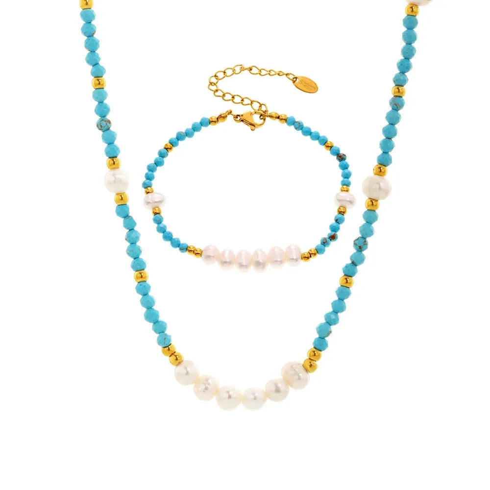 Studio shot of a 2-piece handcrafted jewelry set including a turquoise beaded necklace and matching bracelet with freshwater pearl accents