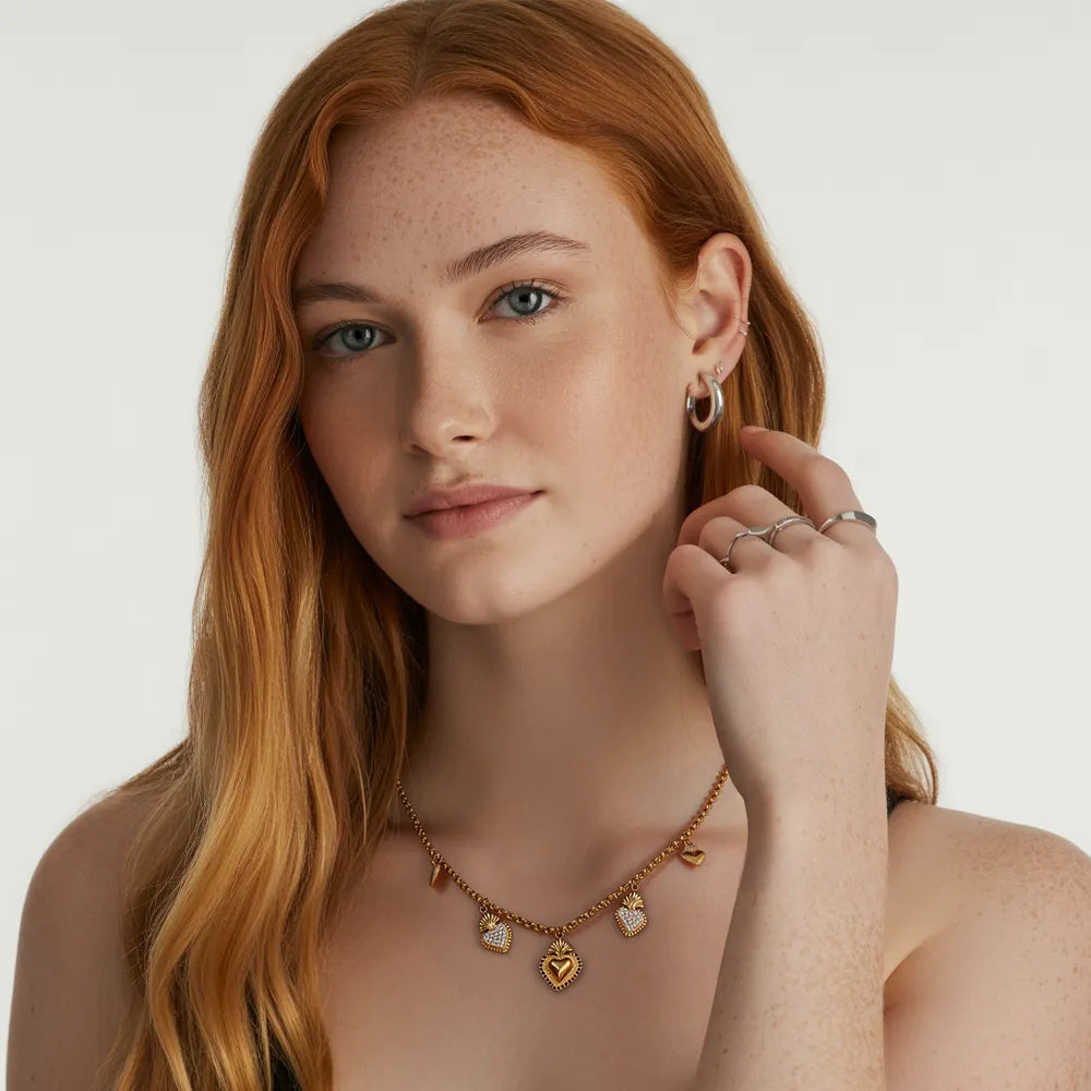 Side profile of a woman showcasing the 18k gold sacred heart charm necklace against a black top