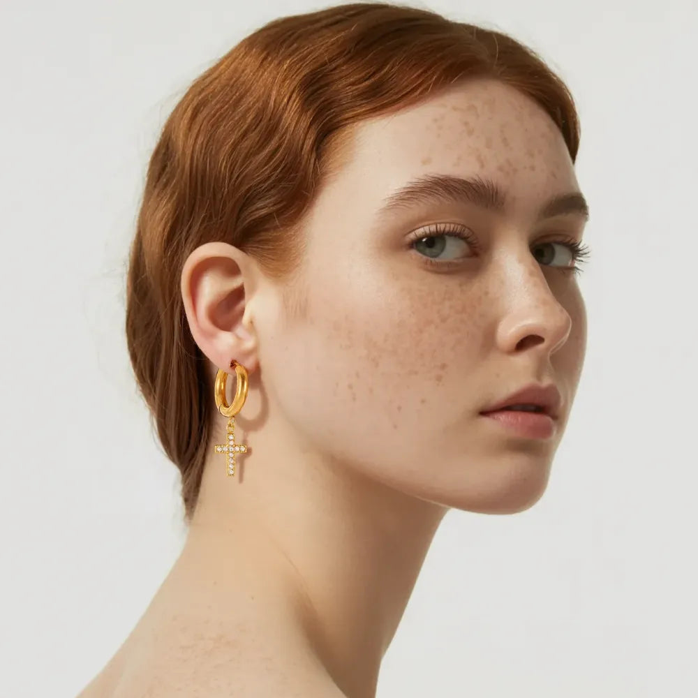 Woman wearing gold dangling cross earrings with a casual outfit.